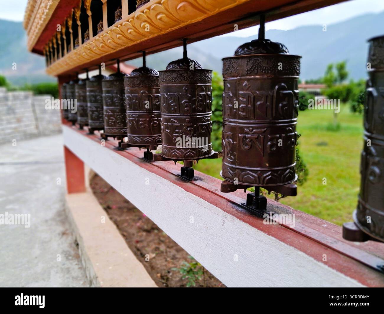Foto ravvicinata della tradizionale ruota di preghiera buddista presso il monastero di Dirang, Arunachal Pradesh, India. La ruota è adornata con mantra sacri in scrittura tibetana Foto Stock