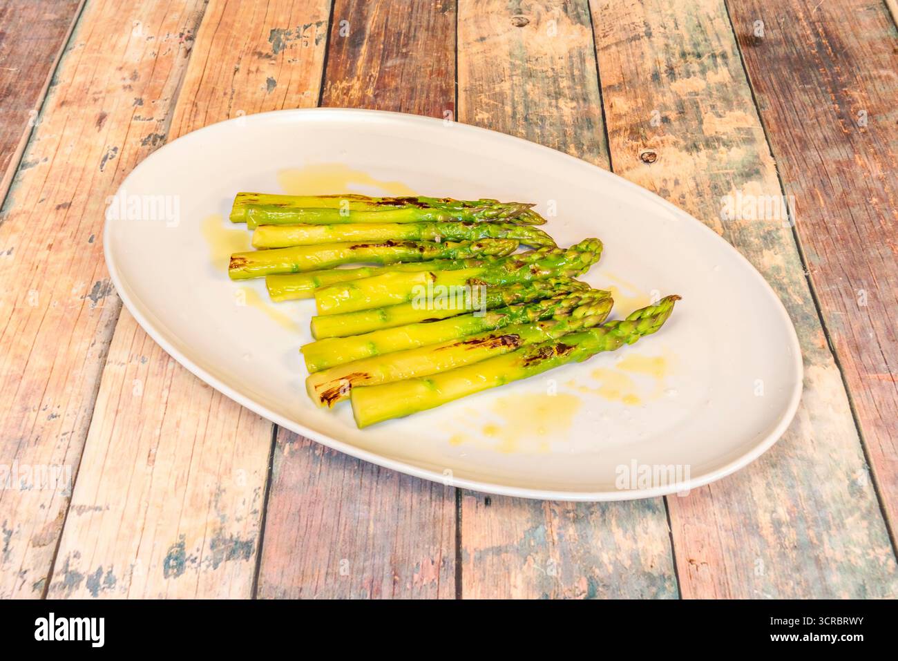 Una selezione di verdure alla griglia, con asparagi selvatici come pezzo forte, mais dolce e peperoni piquillo su una base di crema all'aglio arrosto Foto Stock