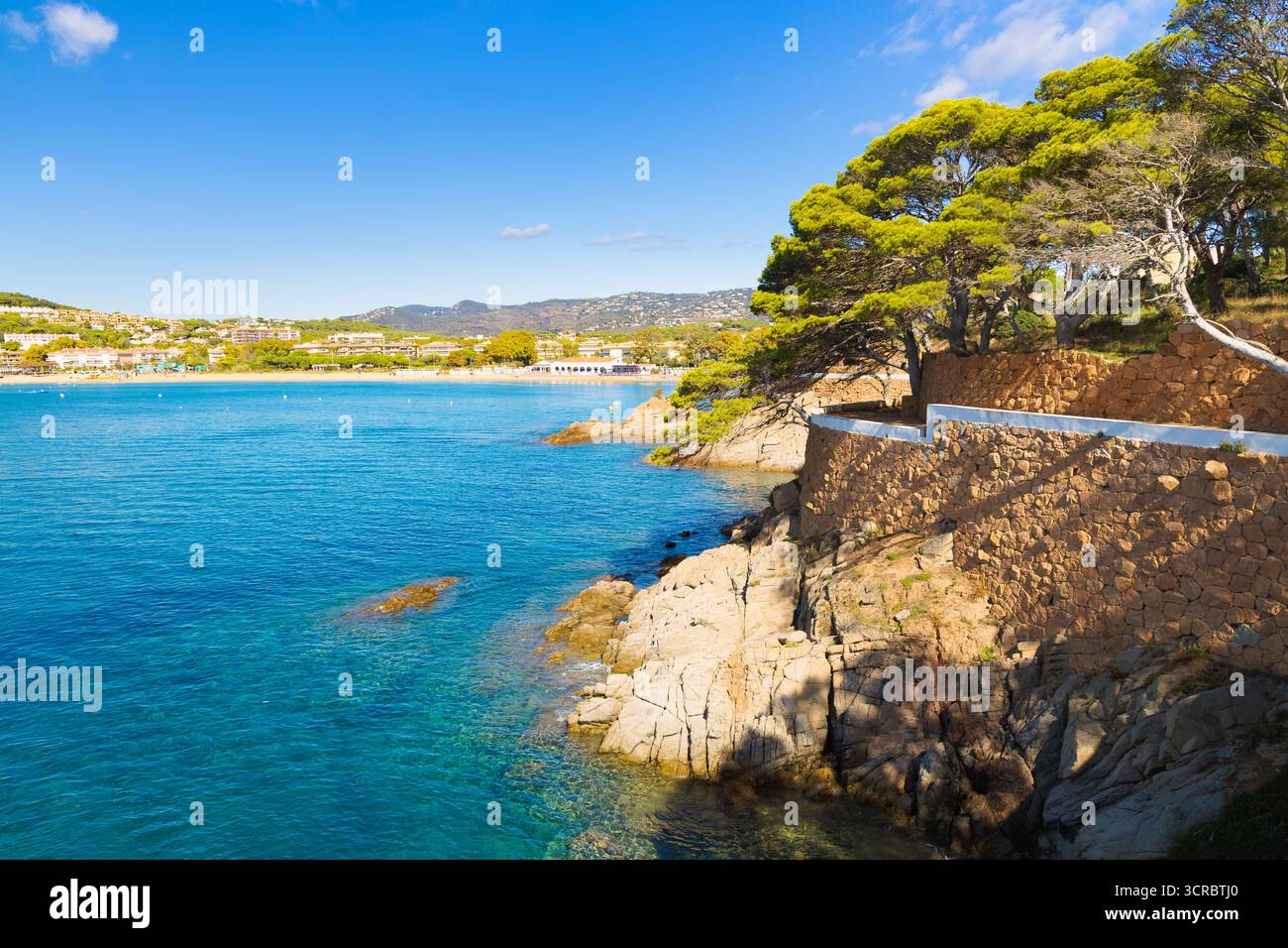 Costa rocciosa di S'Agaró in Costa Brava con pini, muretti in pietra e acque turchesi che si affacciano sulla spiaggia e sulle colline lontane. Foto Stock