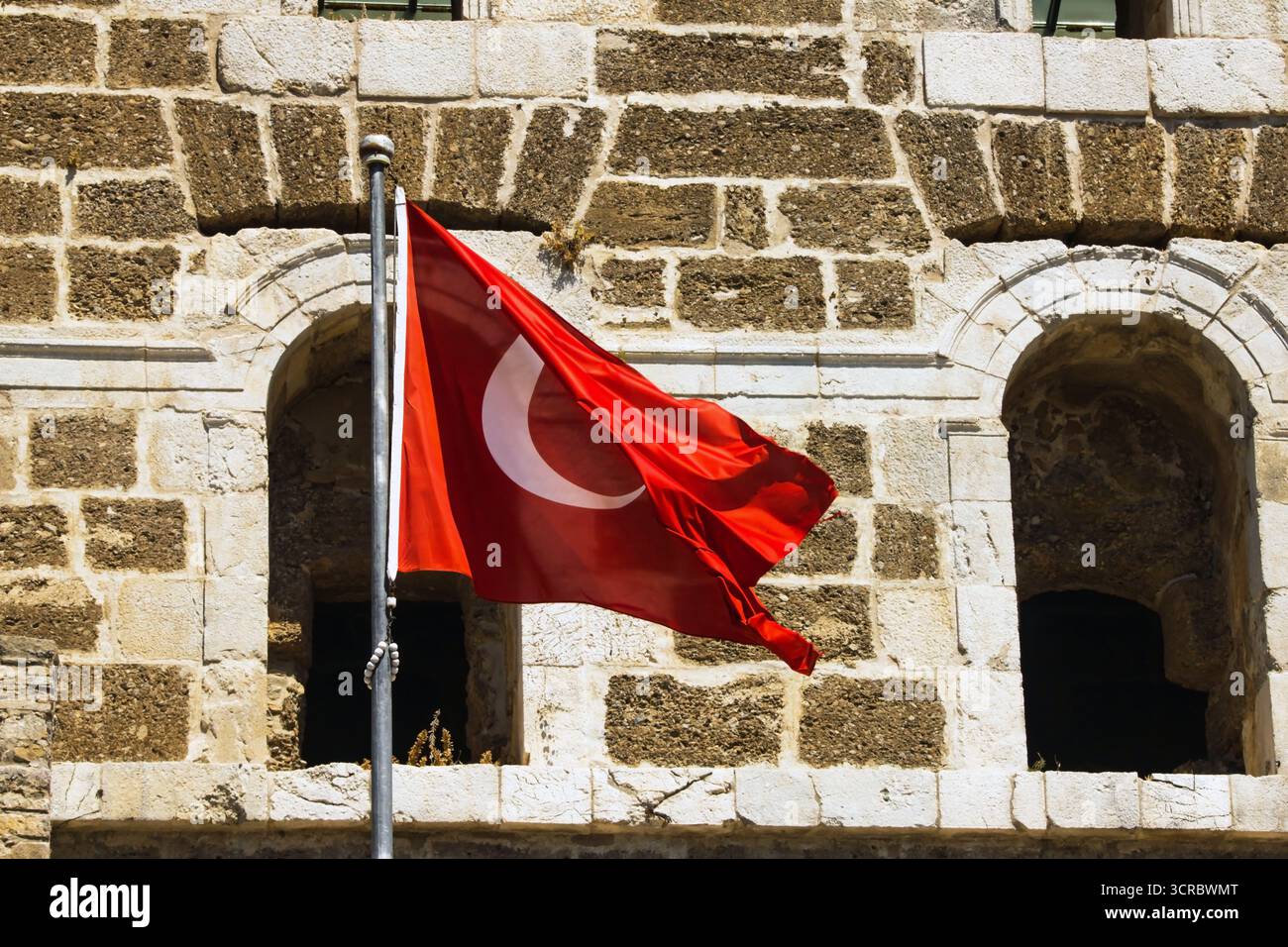 Bandiera turca che sventola di fronte all'antico teatro di Aspendos-Antalya in Turchia Foto Stock