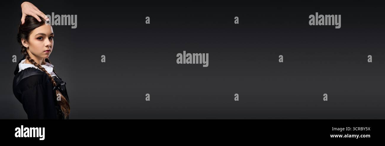 Una ragazza con trecce indossa un abito gotico per festeggiare Halloween con stile Foto Stock