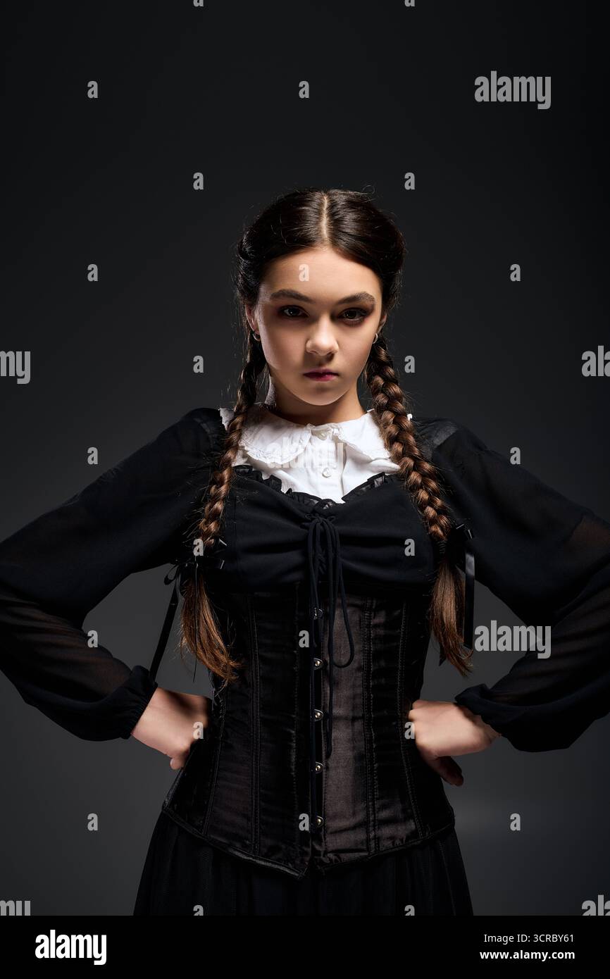 Una ragazza con i capelli intrecciati indossa un abito gotico del mercoledì, incarnando un personaggio spaventoso per Halloween. Foto Stock