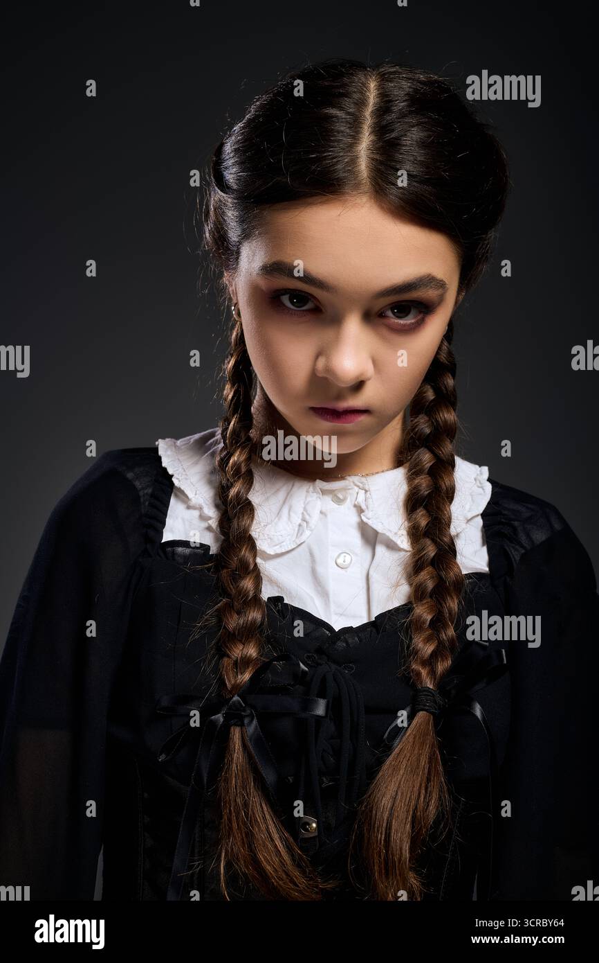 Una ragazza con trecce indossa un abito gotico che ricorda il mercoledì. Foto Stock
