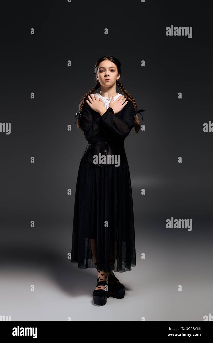 Una ragazza con i capelli intrecciati indossa un abito gotico ispirato a un inquietante personaggio del mercoledì durante Halloween. Foto Stock