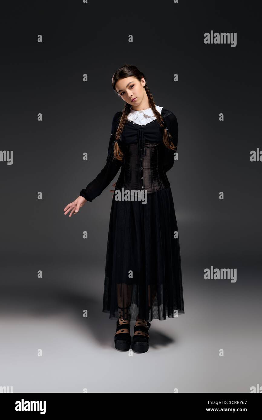 Una ragazza con trecce indossa un abito gotico del mercoledì, incarnando un personaggio perfetto per Halloween. Foto Stock