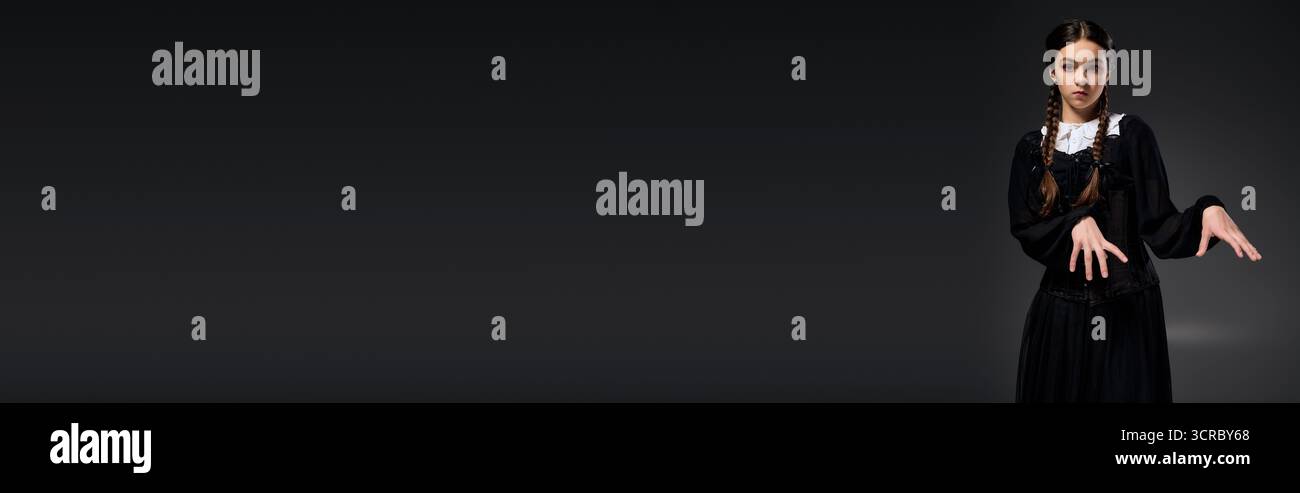 Una ragazza in treccia indossa un abito gotico del mercoledì, abbracciando lo spirito spettrale di Halloween, lo striscione Foto Stock