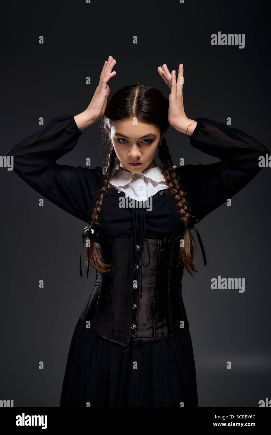 Una ragazza con trecce indossa un abito gotico che ricorda un personaggio spaventoso per Halloween. Foto Stock