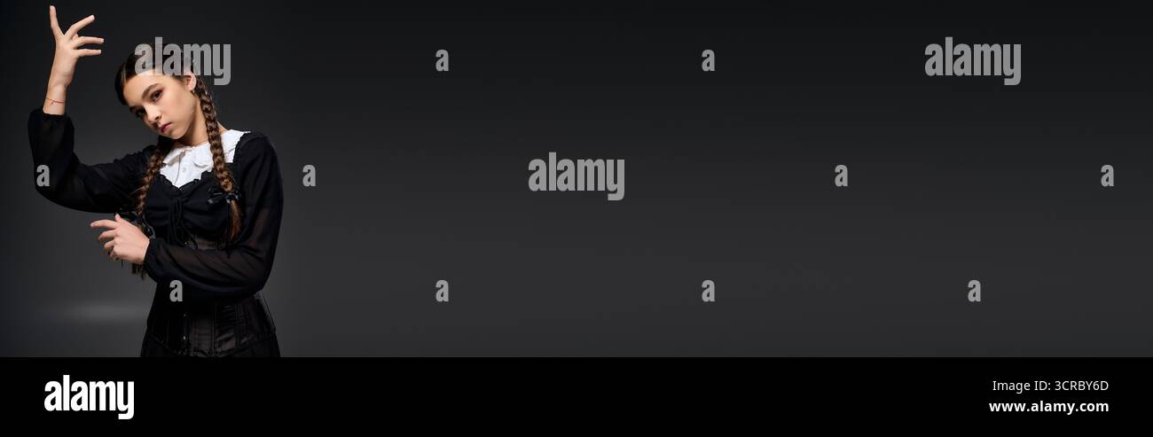 Una ragazza con trecce indossa un abito gotico del mercoledì, abbracciando lo spirito di Halloween con una posa misteriosa, uno striscione Foto Stock