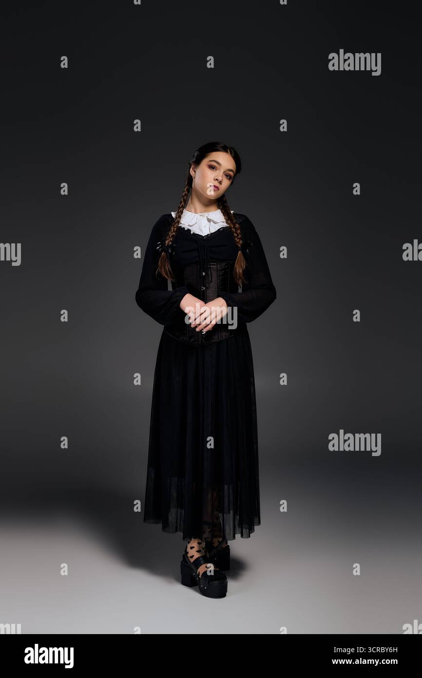 Una ragazza con un abito gotico mercoledì con trecce si posa elegantemente durante la stagione di Halloween. Foto Stock