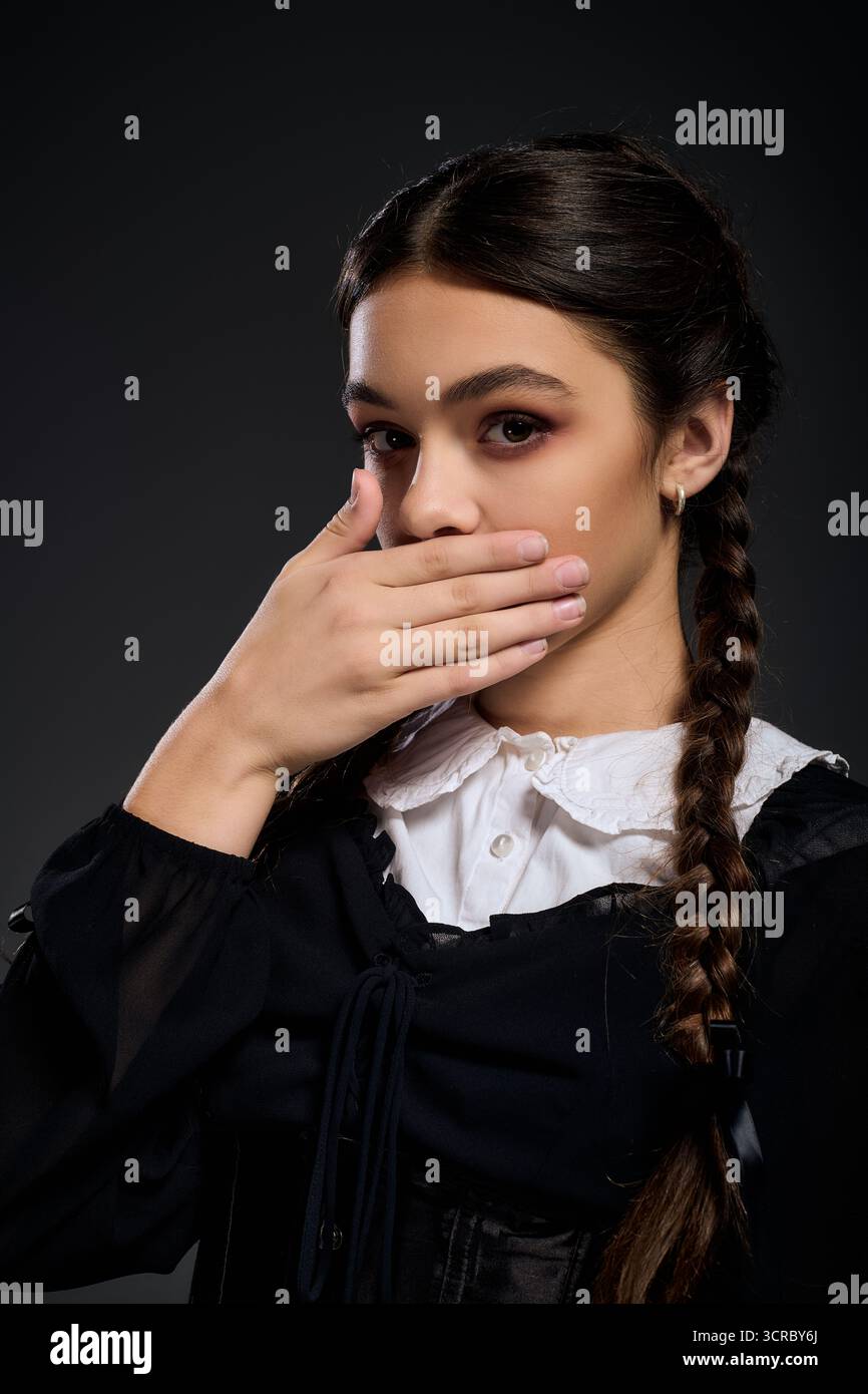 Una ragazza con trecce indossa un abito gotico, che incarna un personaggio del mercoledì per Halloween. Foto Stock