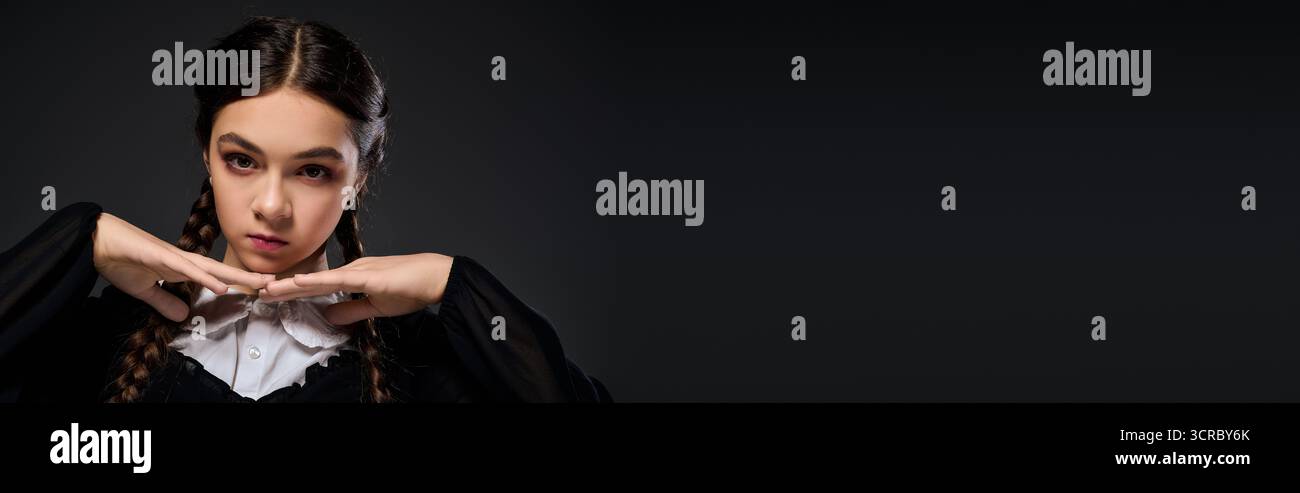 Una ragazza vestita in stile gotico mercoledì posa drammaticamente per Halloween, striscione Foto Stock