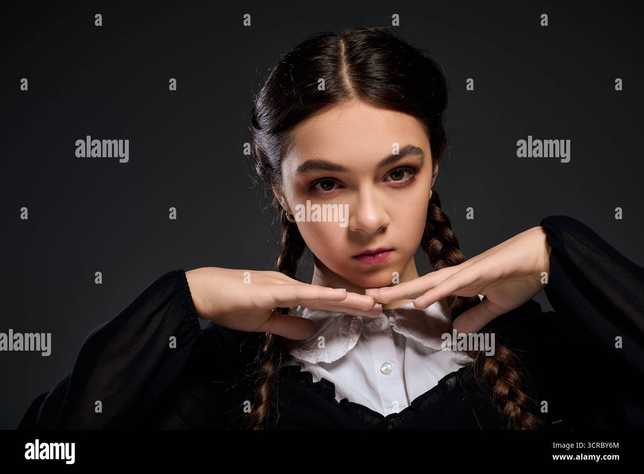Una ragazza con trecce indossa un abito mercoledì in stile gotico, che incarna un personaggio spaventoso per Halloween. Foto Stock