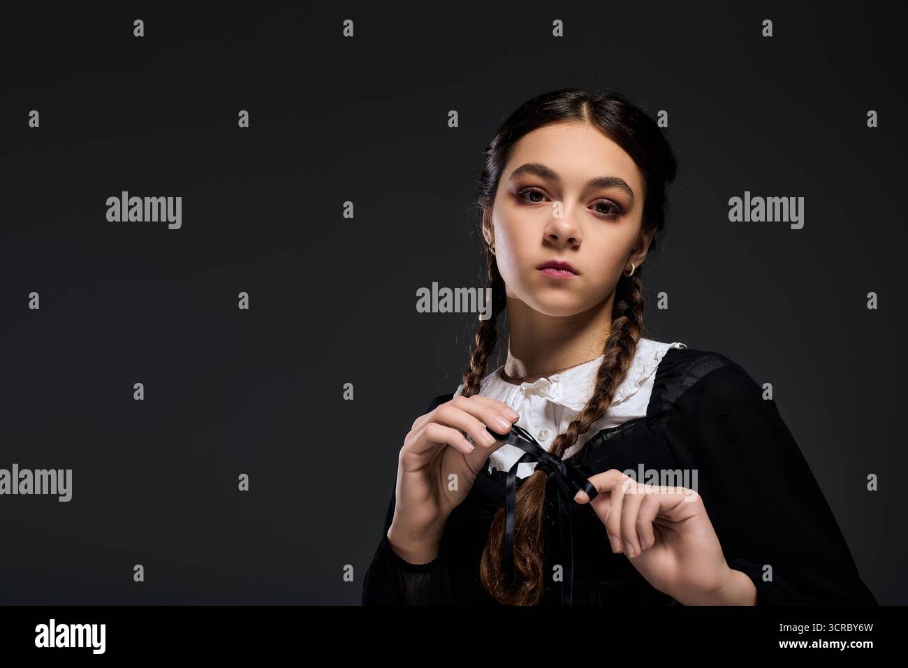 Una ragazza con trecce indossa un abito in stile gotico, incarnando un personaggio eccentrico per Halloween. Foto Stock