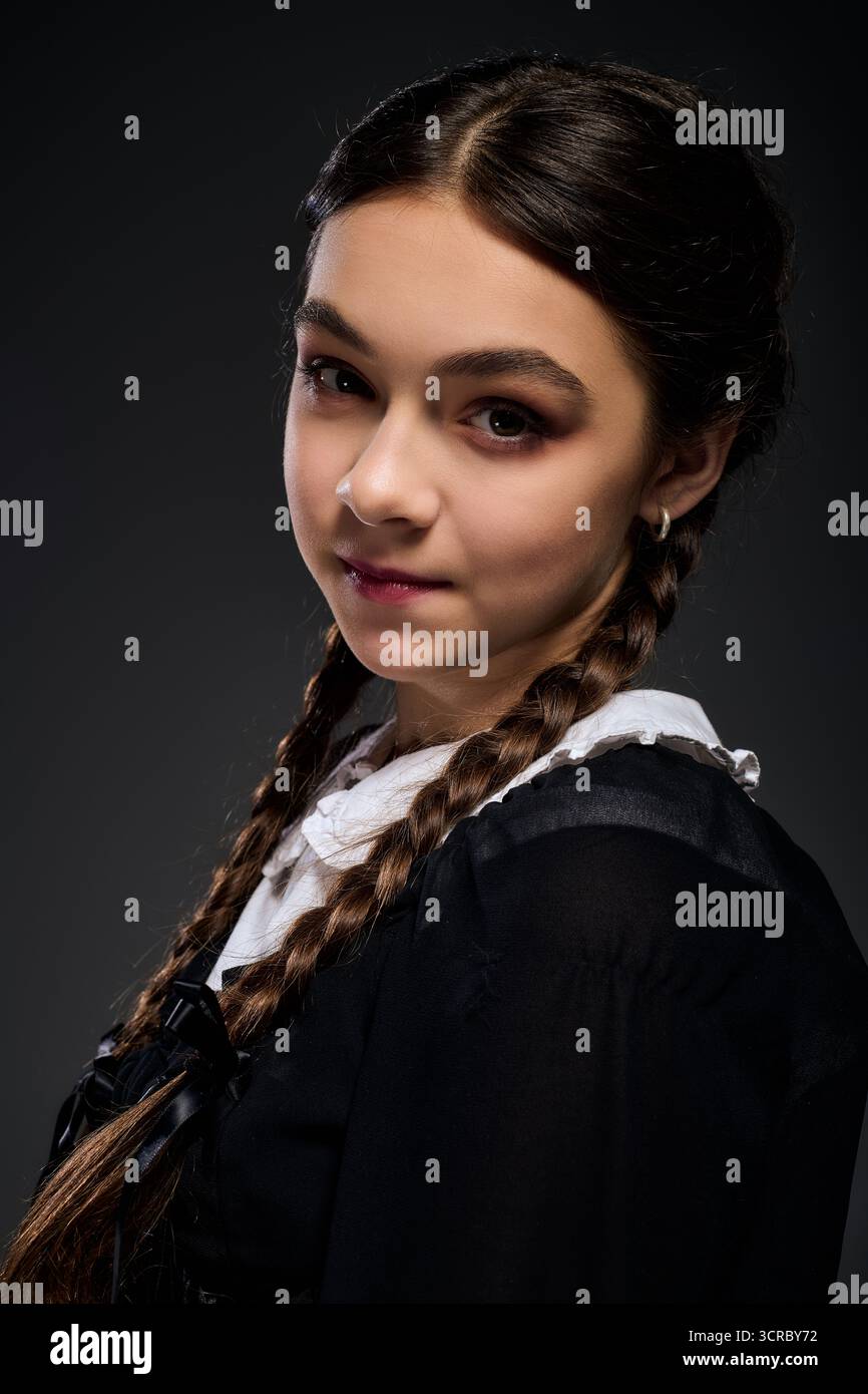 Una ragazza in treccia indossa un abito gotico del mercoledì, che incarna perfettamente lo spirito di Halloween. Foto Stock