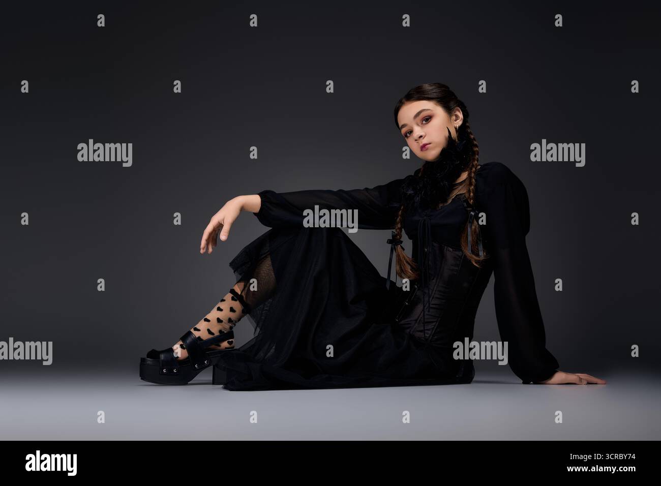 Una ragazza con trecce indossa un abito gotico ispirato a un personaggio spaventoso del mercoledì Foto Stock