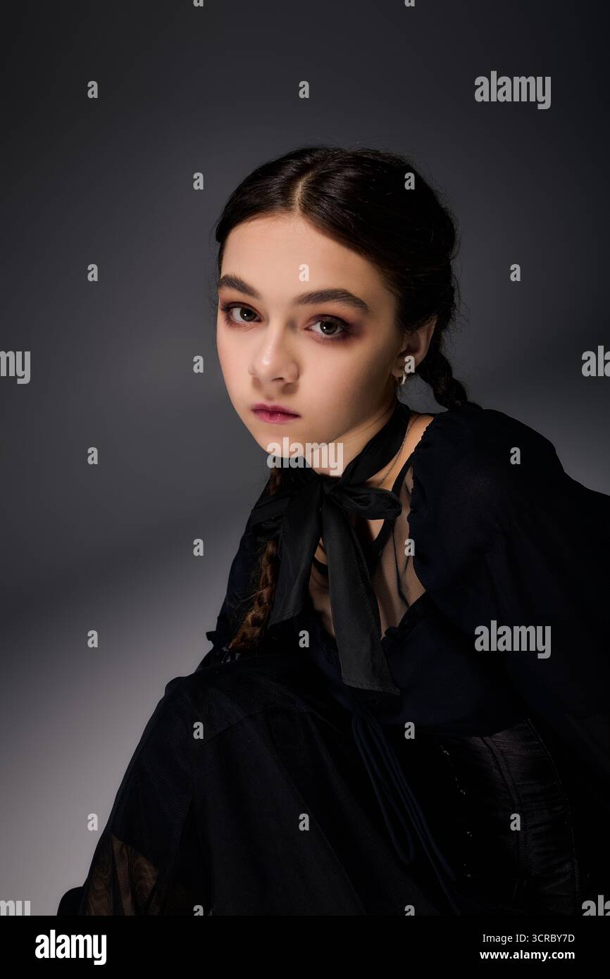 Una ragazza con trecce indossa un abito gotico del mercoledì, catturando l'essenza dello spirito di Halloween. Foto Stock