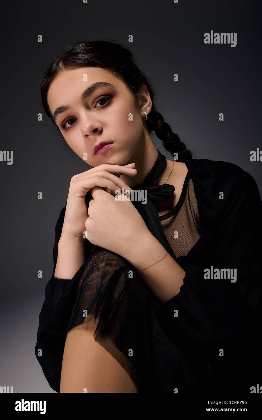 Una ragazza con trecce si posa in un abito scuro del mercoledì, catturando perfettamente lo spirito di Halloween. Foto Stock