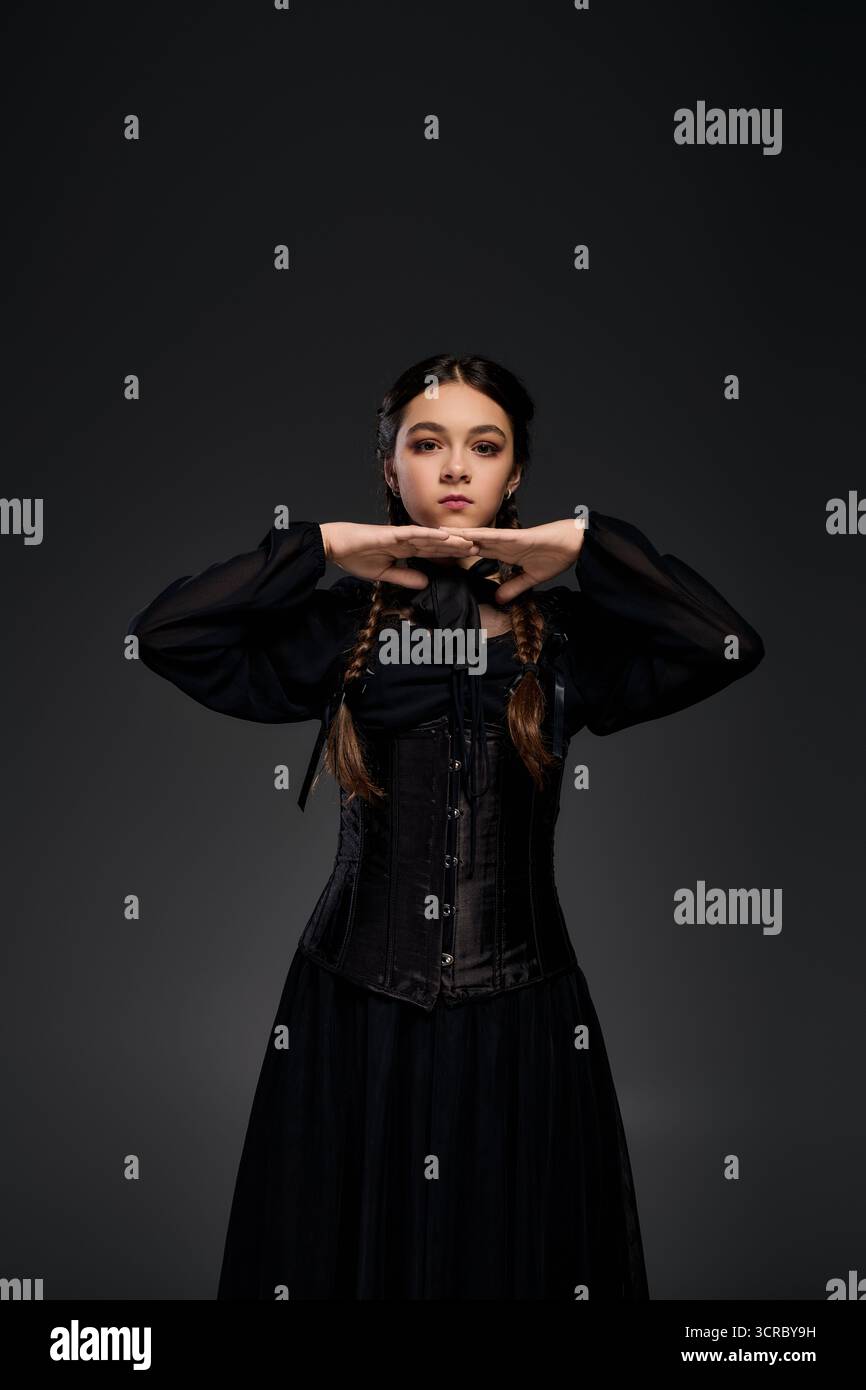 Una ragazza con trecce indossa un abito in stile gotico ispirato al mercoledì di Halloween. Foto Stock