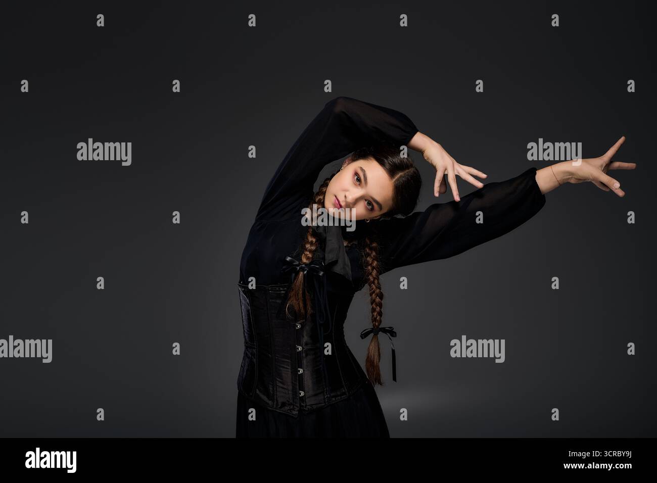 Una ragazza con trecce indossa un abito gotico del mercoledì, che incarna un personaggio per le feste di Halloween. Foto Stock