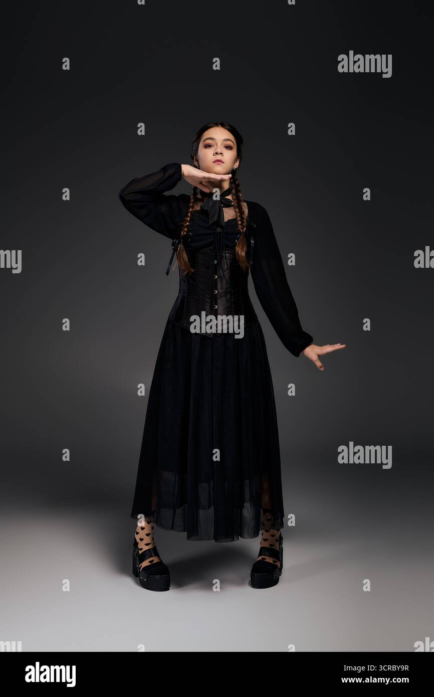 Una ragazza con trecce posa in un abito gotico del mercoledì per Halloween, mostrando il suo carattere spettrale. Foto Stock