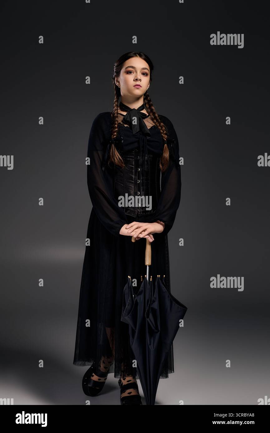 Una ragazza con trecce indossa un abito gotico ispirato a uno spaventoso personaggio del mercoledì, che abbraccia lo spirito di Halloween. Foto Stock