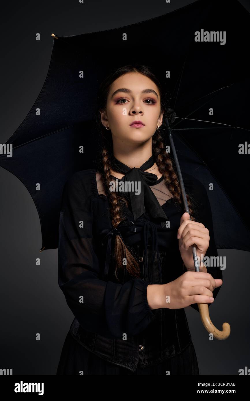 Una ragazza vestita in stile gotico mercoledì si erge in piedi con un ombrello durante la stagione spettrale. Foto Stock