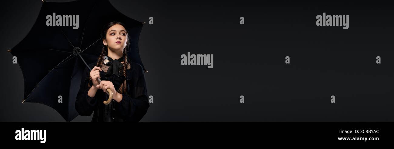 Una ragazza con trecce indossa un abito gotico, incarnando un personaggio spaventoso per il divertimento di Halloween, banner Foto Stock