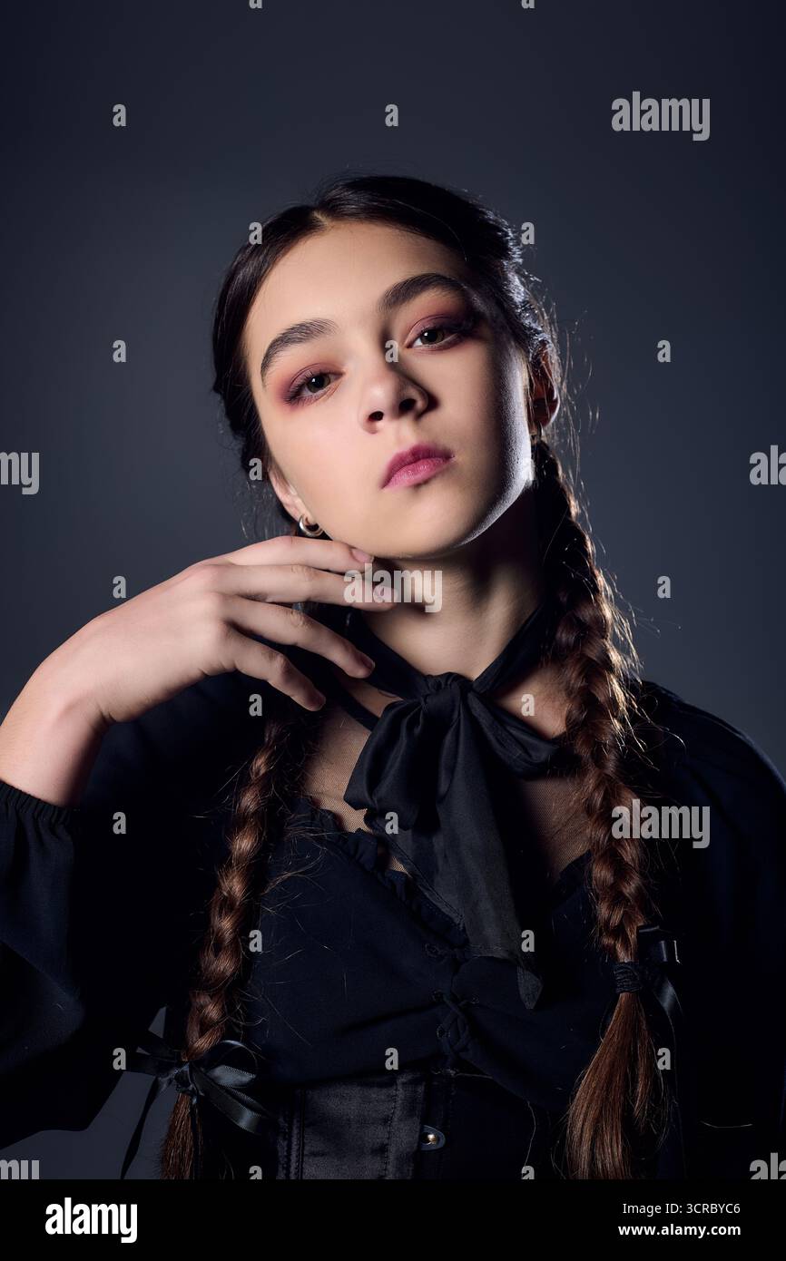 Una ragazza con trecce si posa in un abito gotico, abbracciando lo spirito di Halloween e la stagione spettrale. Foto Stock