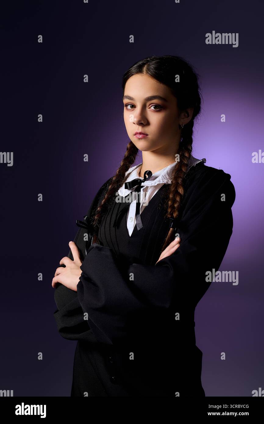 Un bambino con trecce indossa un abito di Halloween in stile gotico, che incarna un personaggio spaventoso del mercoledì. Foto Stock