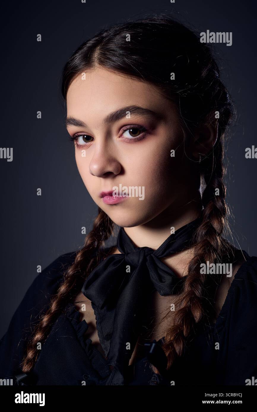 Una ragazza con trecce indossa un abito gotico ispirato a un popolare personaggio di Halloween. Foto Stock