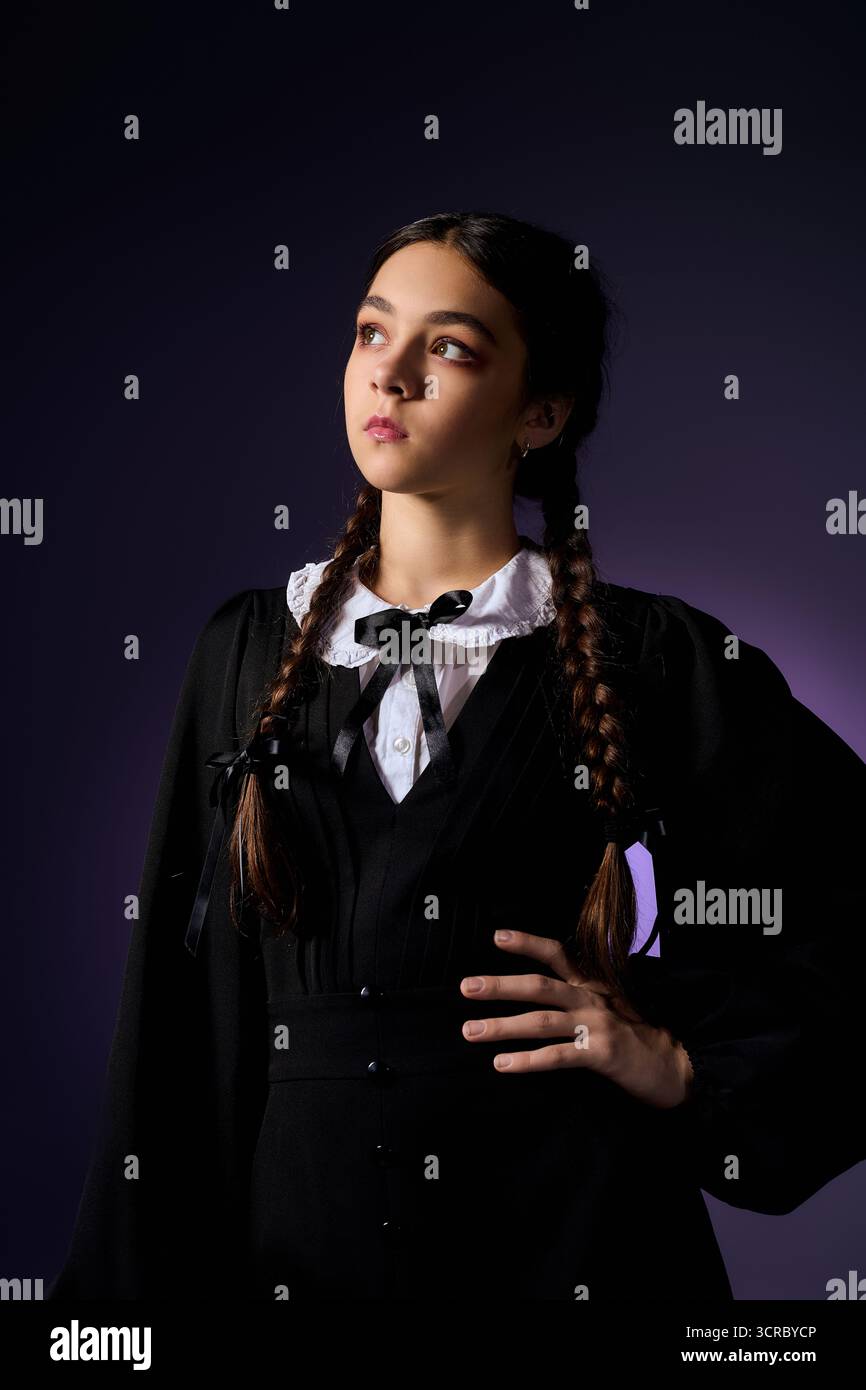 Una ragazza con trecce si posa elegantemente in un abito gotico del mercoledì, celebrando le vibrazioni di Halloween a ottobre. Foto Stock