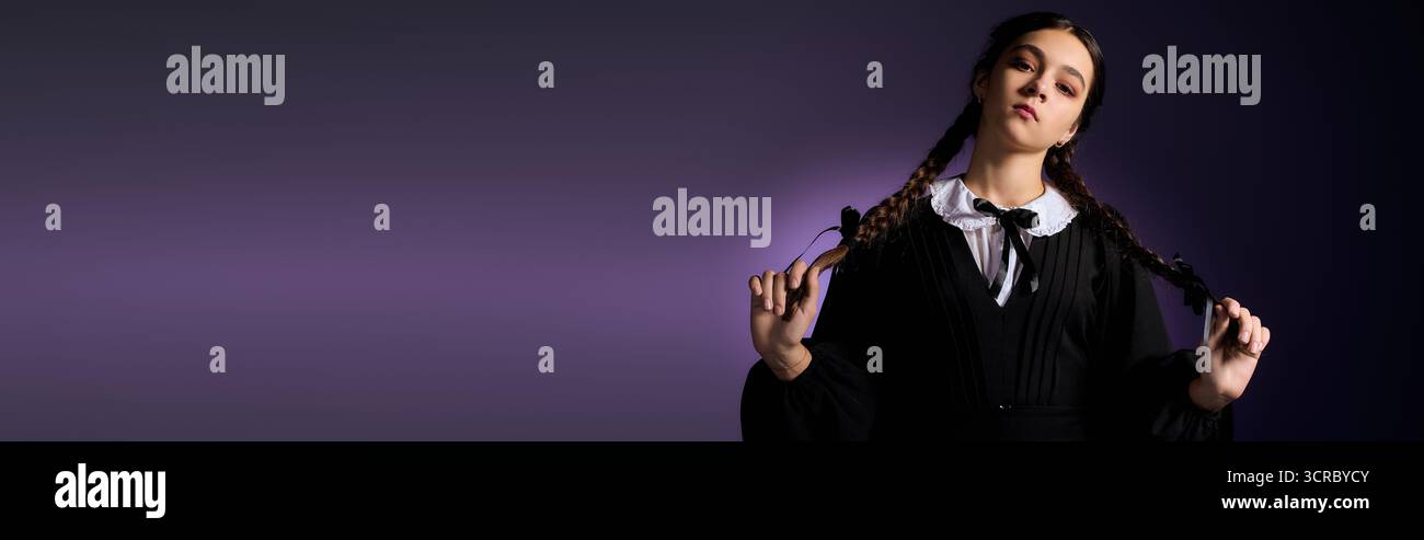Una ragazza con trecce vestita con un costume gotico mercoledì gode di un momento spaventoso, uno striscione Foto Stock