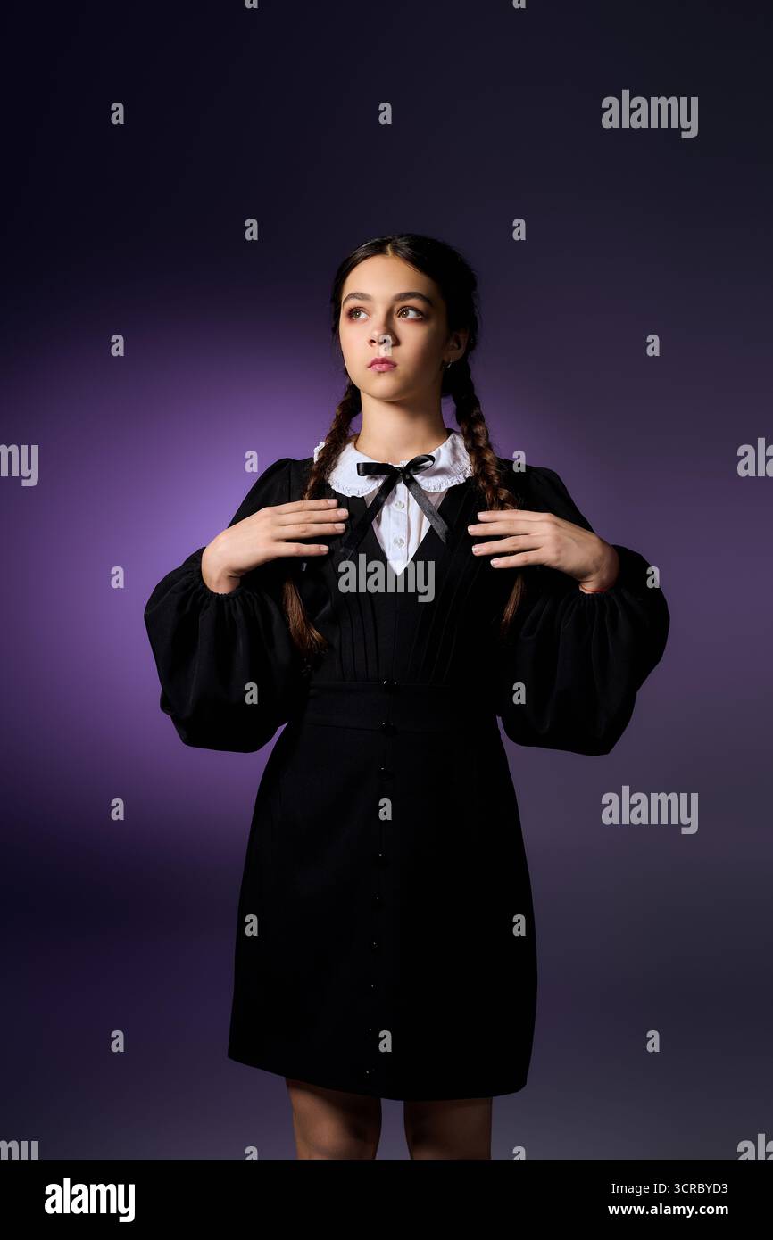 Una ragazza con trecce si posa in un abito gotico, incarnando l'essenza del mercoledì per Halloween. Foto Stock