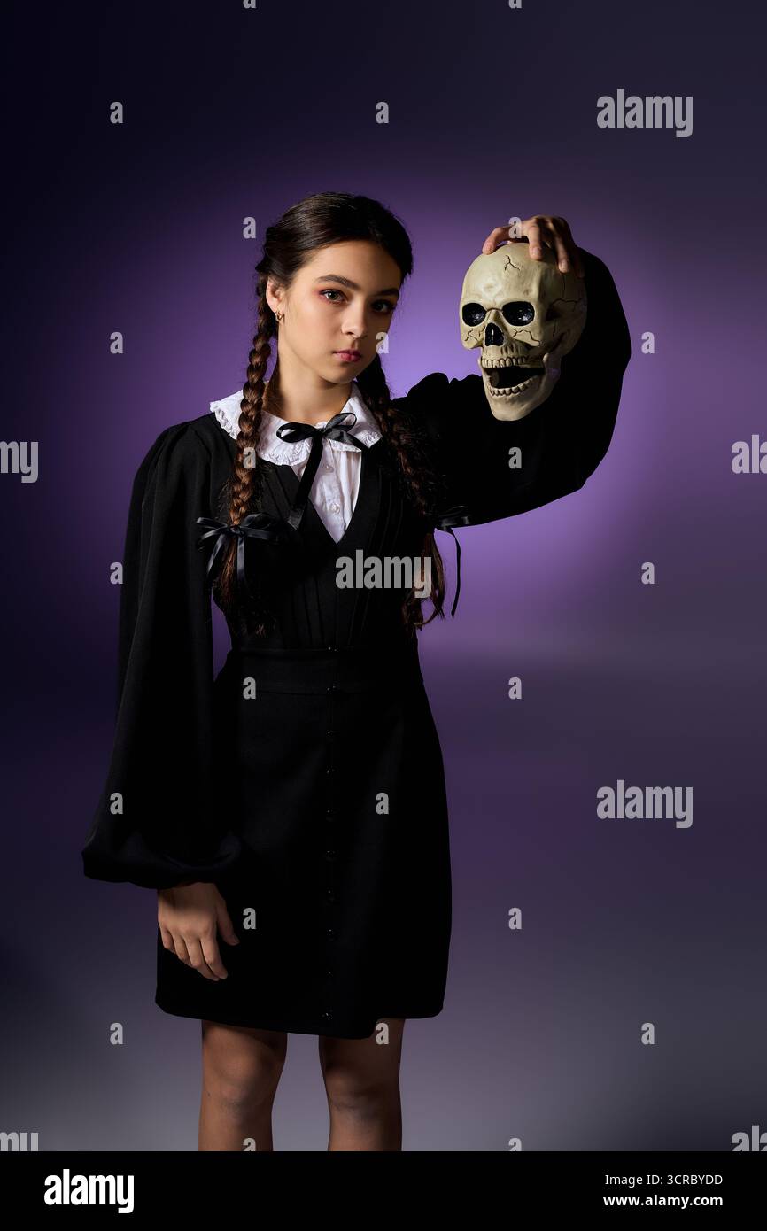Una ragazza con trecce indossa un abito in stile gotico, con il teschio, che abbraccia la stagione spettrale. Foto Stock