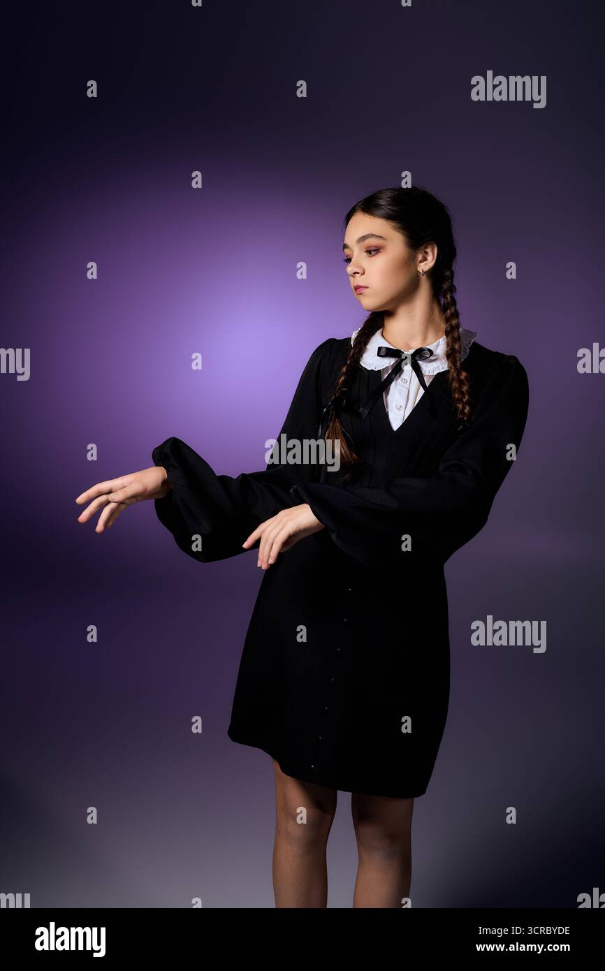 Un bambino con trecce indossa un abito a tema gotico, raffigurante il mercoledì per le festività di Halloween. Foto Stock