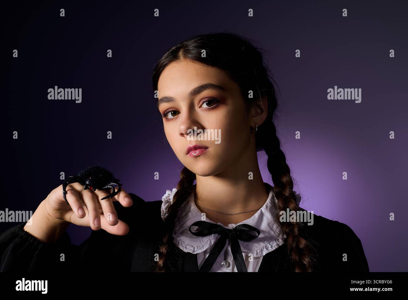 Una ragazza con trecce vestita con un abito gotico cattura lo spirito di Halloween con fiducia. Foto Stock