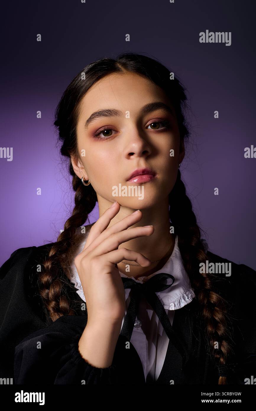 Una ragazza con trecce in abito gotico incarna il personaggio del mercoledì per le festività di Halloween. Foto Stock