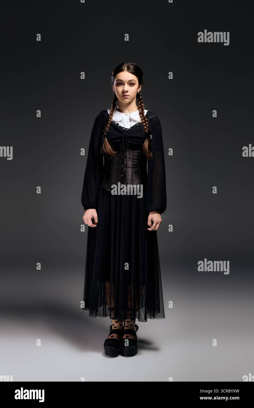 Una ragazza con trecce indossa un abito gotico ispirato al personaggio del mercoledì durante il periodo di Halloween. Foto Stock