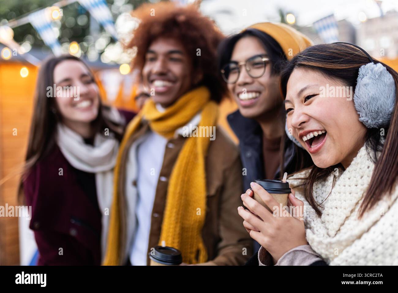 Amici multietnici felici che si gusteranno bevande calde al mercatino di natale Foto Stock