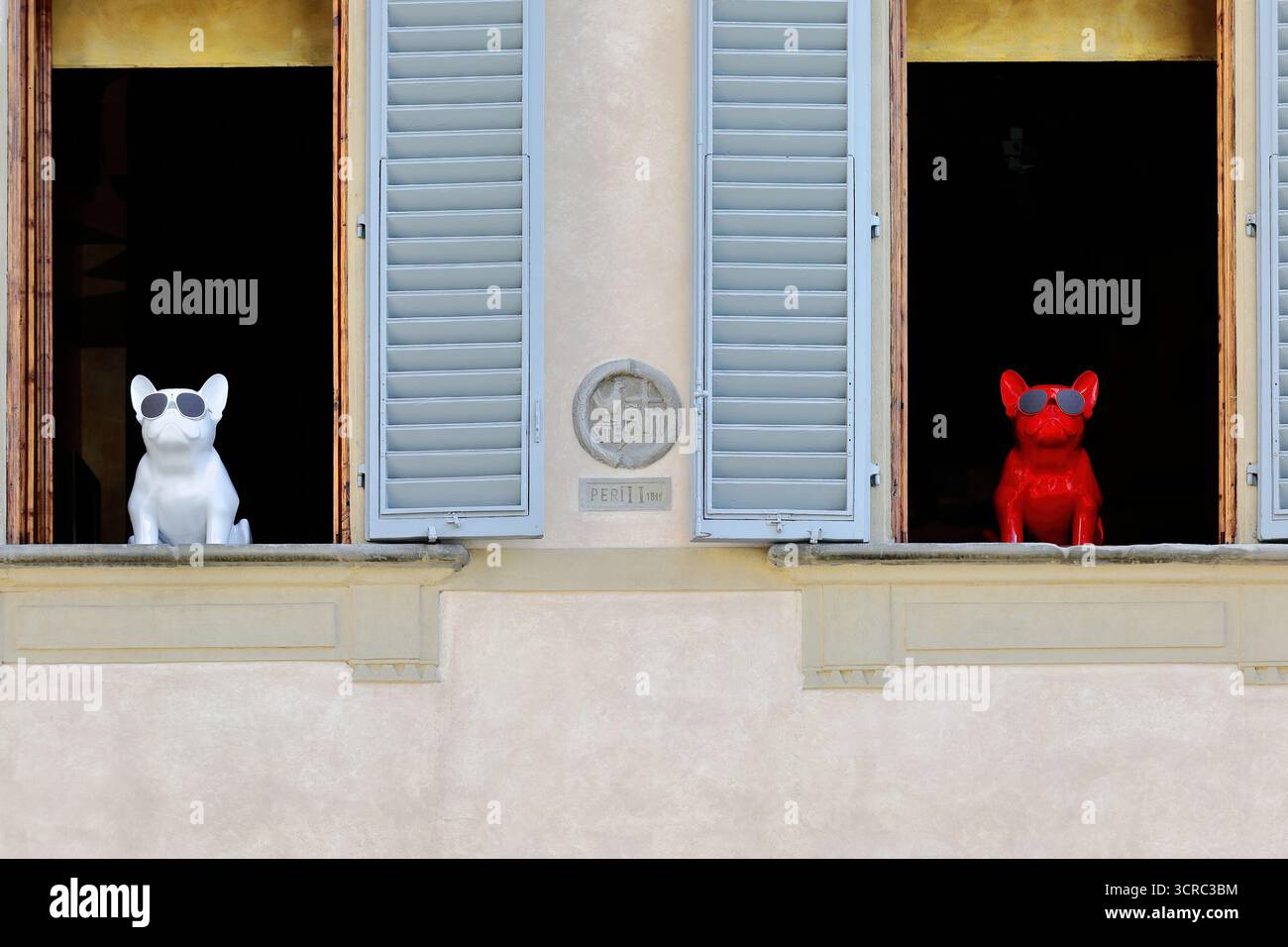 384 statuette in plastica bulldog francese con occhiali da sole in bianco e rosso, su due sporgenze della finestra del Palazzo Orfanotrofio del Bigallo. Firenze-Toscana. Foto Stock
