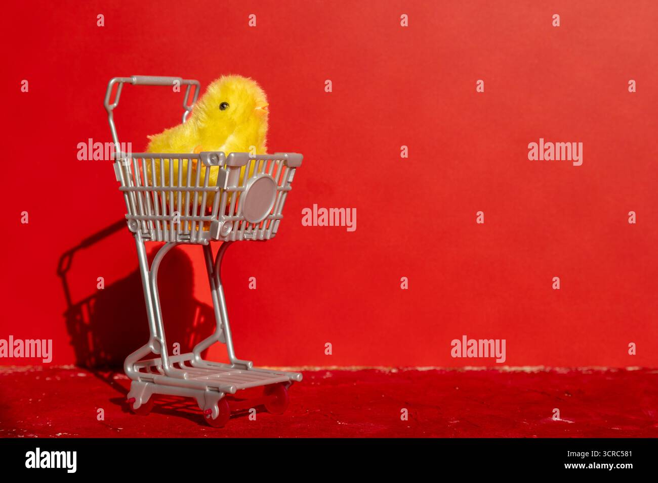 Carino piccolo pulcino all'interno di un carrello è solo su uno sfondo rosso. Concettuale. Foto Stock