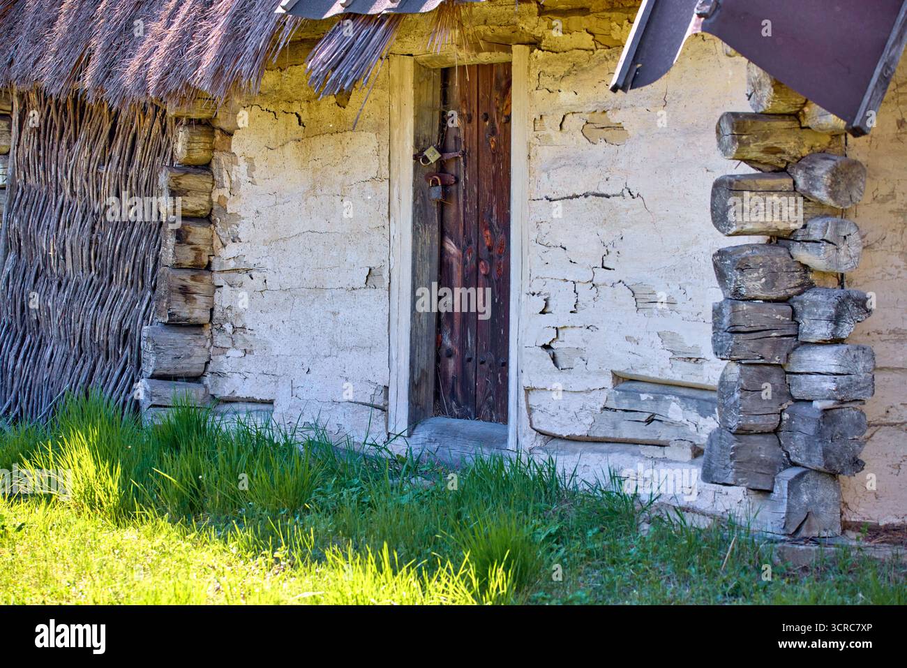 immagini di lucchetti appesi su vecchie porte in legno in una parete di tronchi rivestiti di argilla bianca Foto Stock