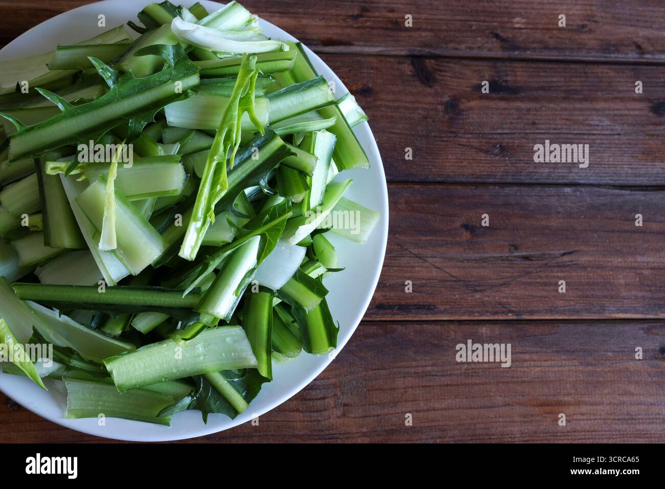 Cicoria tritata in Catalogna o cicoria di asparagi isolata su fondo di legno. Verdure italiane fresche. Cibo sano e vegetariano. Direttamente sopra. Foto Stock