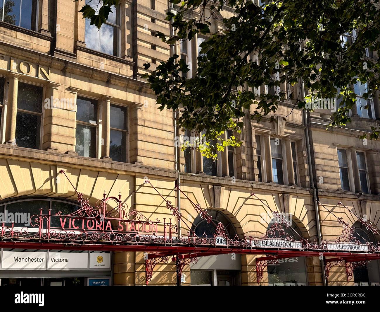 Cartello di lavoro in metallo vinilico sopra l'ingresso della stazione ferroviaria di Manchester Victoria Foto Stock