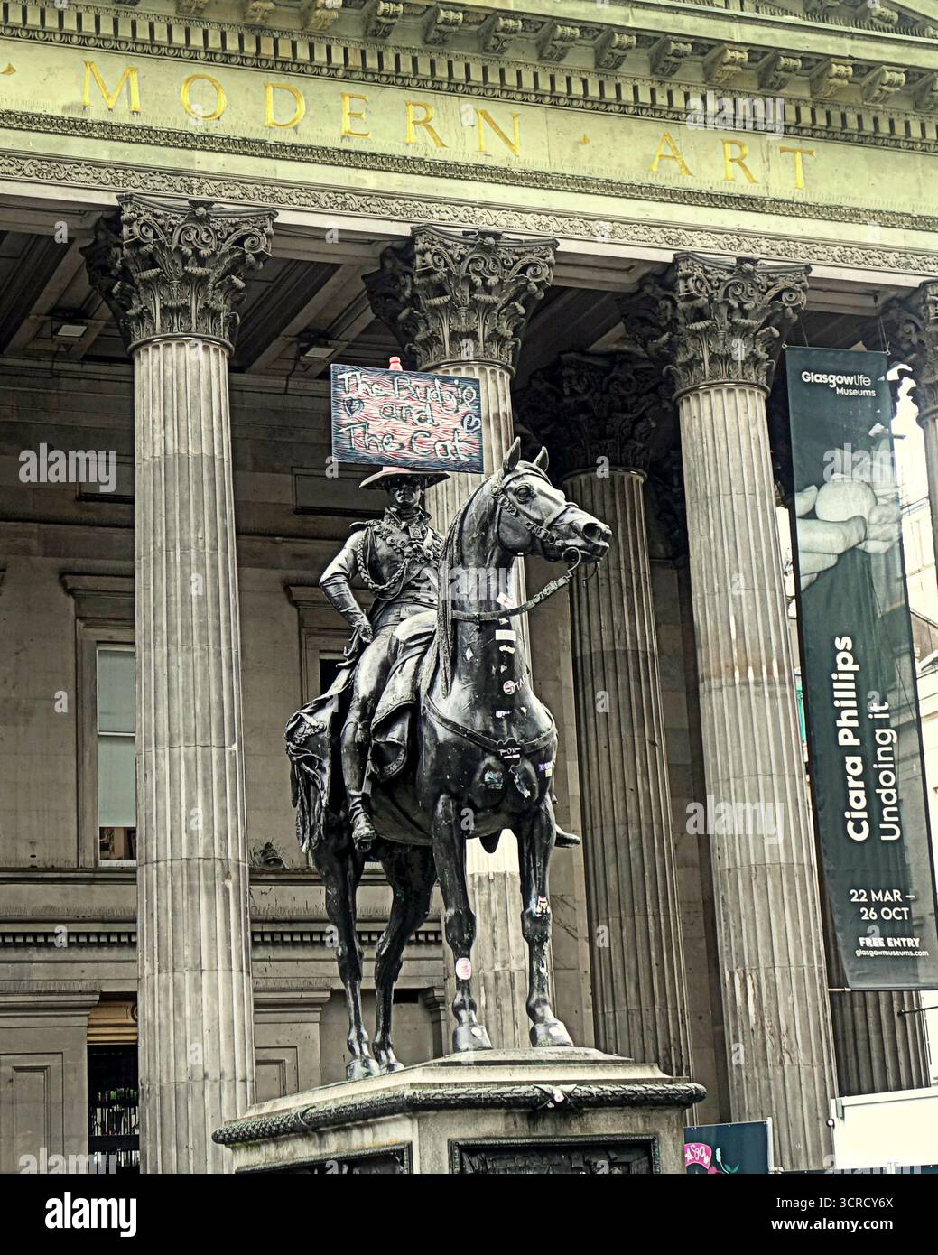 Glasgow, Scozia, Regno Unito. 30 settembre 2025. L'iconica statua della città subisce un attacco artistico quando torna a scuola come una piccola tavola con "il budgie e il gatto" con i cuori dipinti su di essa appare fuori dalla galleria d'arte moderna della città indicando la possibilità di un progetto di studente d'arte o solo di una lettera d'amore . Credit Gerard Ferry/Alamy Live News Foto Stock