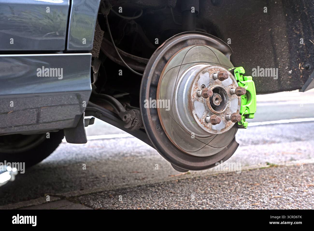 Reifenpanne eines Autos Wechsel eines Autoreifens mit einem Wagenheber mit Blick auf die Bremsanlage **** pneumatico a terra di un'auto che sostituisce una ruota di un'auto con un cric con vista dell'impianto frenante Foto Stock