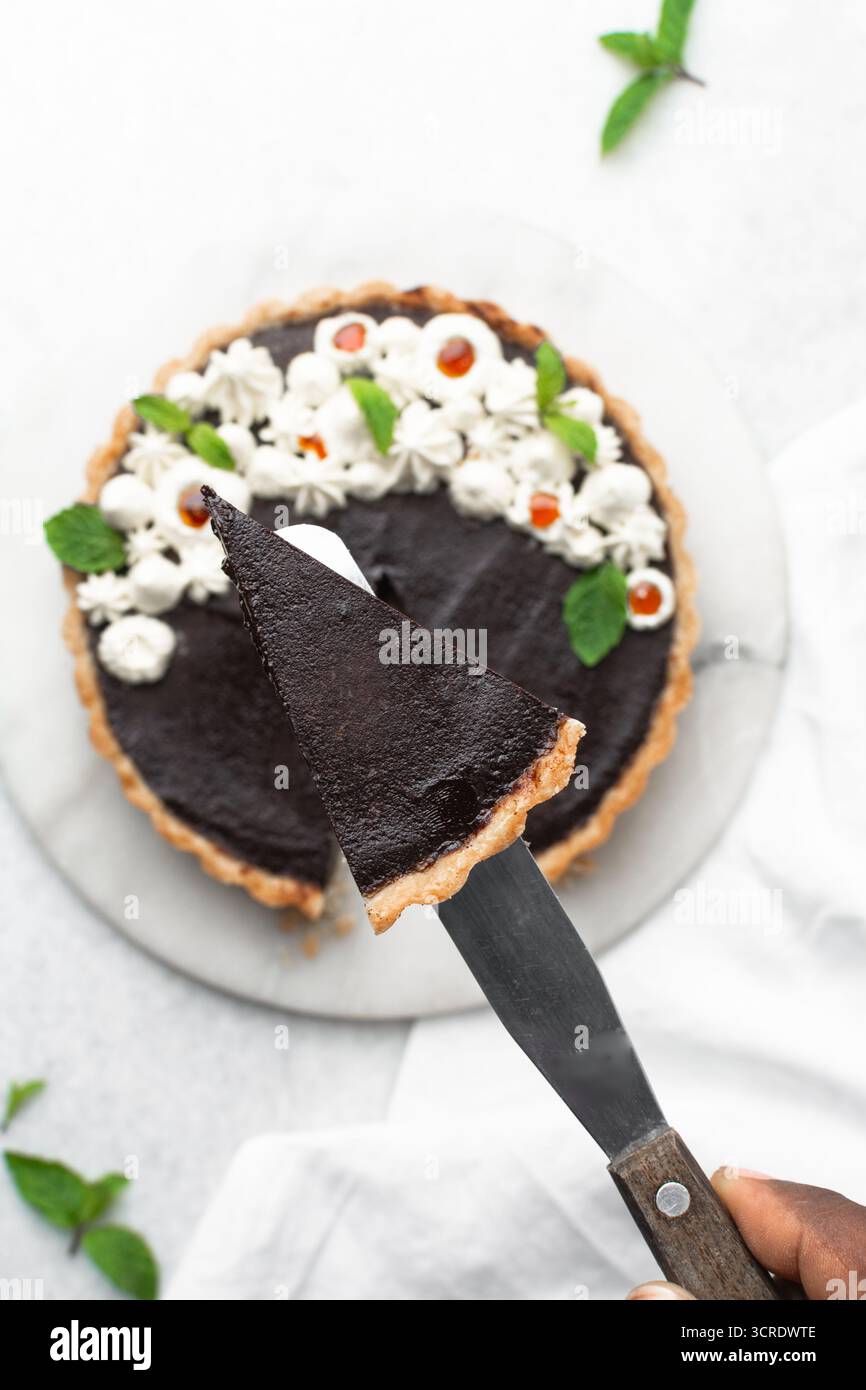 Vista dall'alto di una fetta di crostata al cioccolato su un piatto bianco, vista dall'alto di crostata al cioccolato senza cottura su sfondo bianco, una fetta di torta al cioccolato Foto Stock