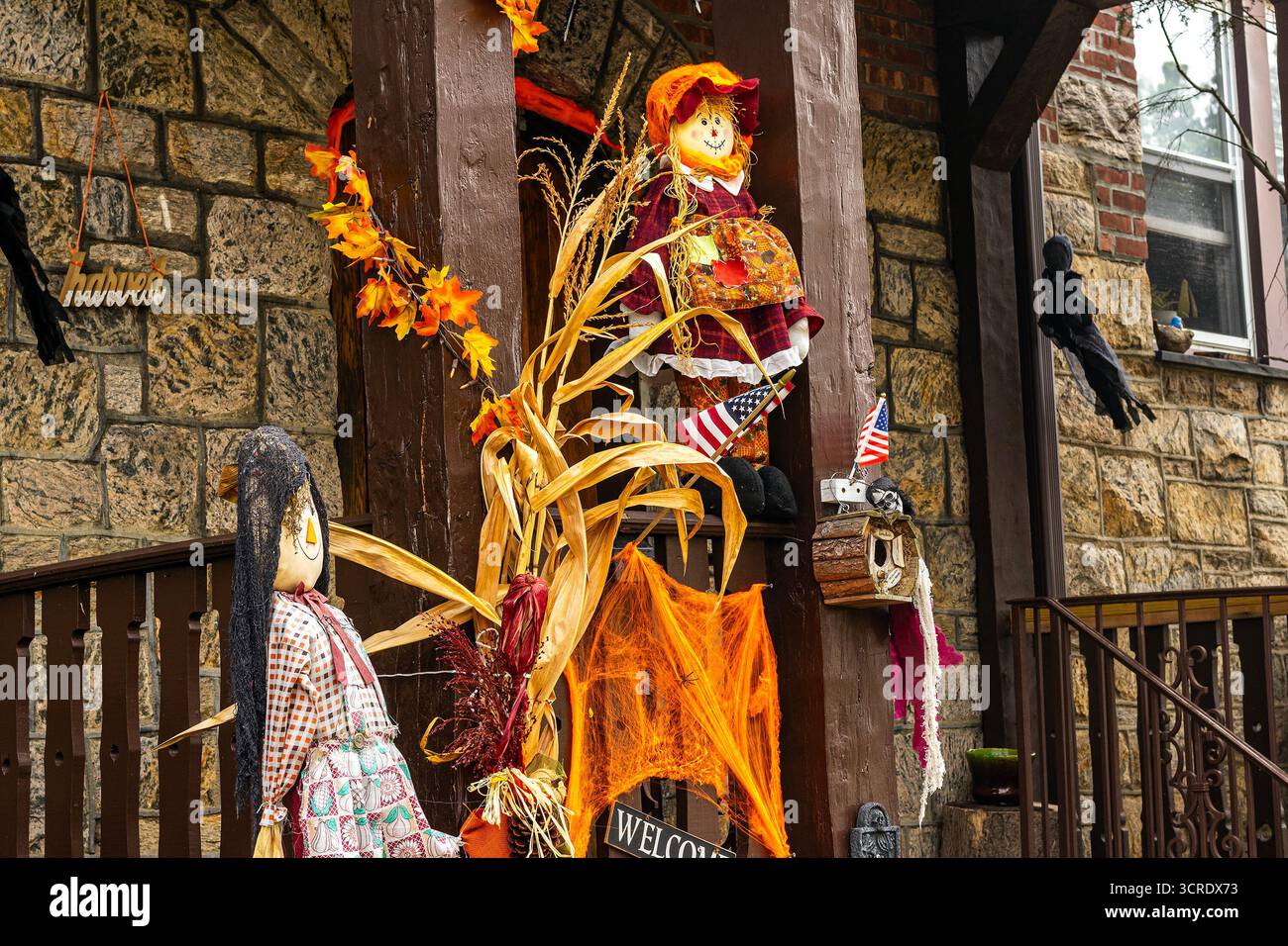 Decorazioni di Halloween su un portico nella campagna del New England, decorazioni per scherzi o dolcetti, decorazioni per il raccolto autunnale con spaventapasseri e gambi di mais Foto Stock