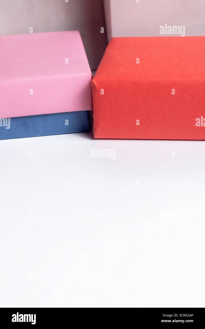 Le luminose confezioni regalo pastello in rosa, arancione e blu creano un'allegra esposizione perfetta per feste, regali e temi natalizi. Foto Stock