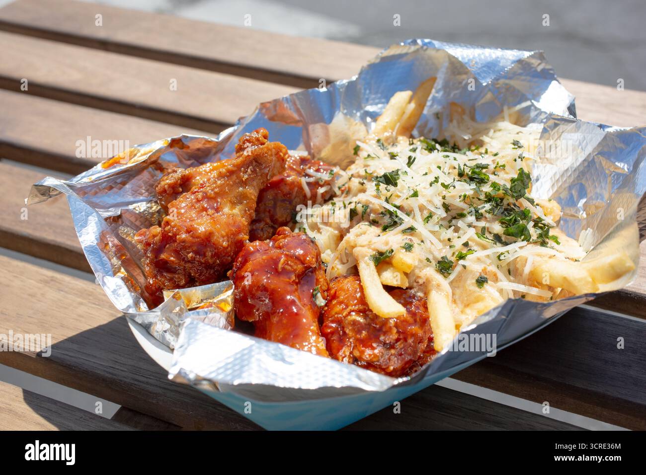 Vista su un cestino di ali di pollo glassate e patatine fritte caricate. Foto Stock